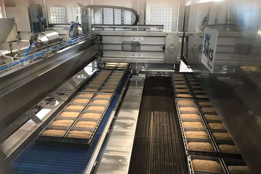 Bakemaster oven infeed pusher system in a biscuit tunnel oven, showcasing conveyor mechanics where RTO integrates for emission capture during baking.